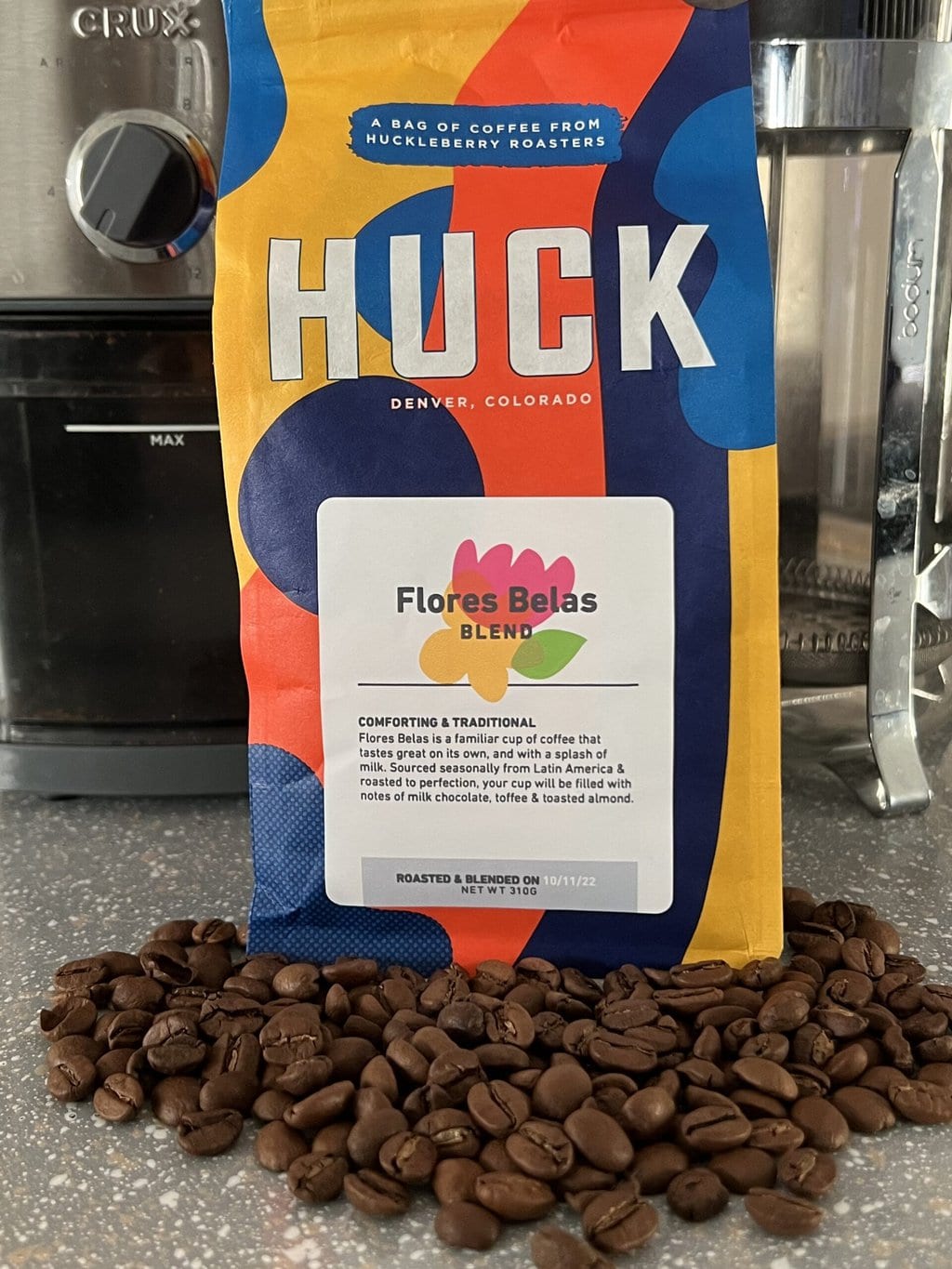 Coffee beans scattered next to a pack of Huck Coffee