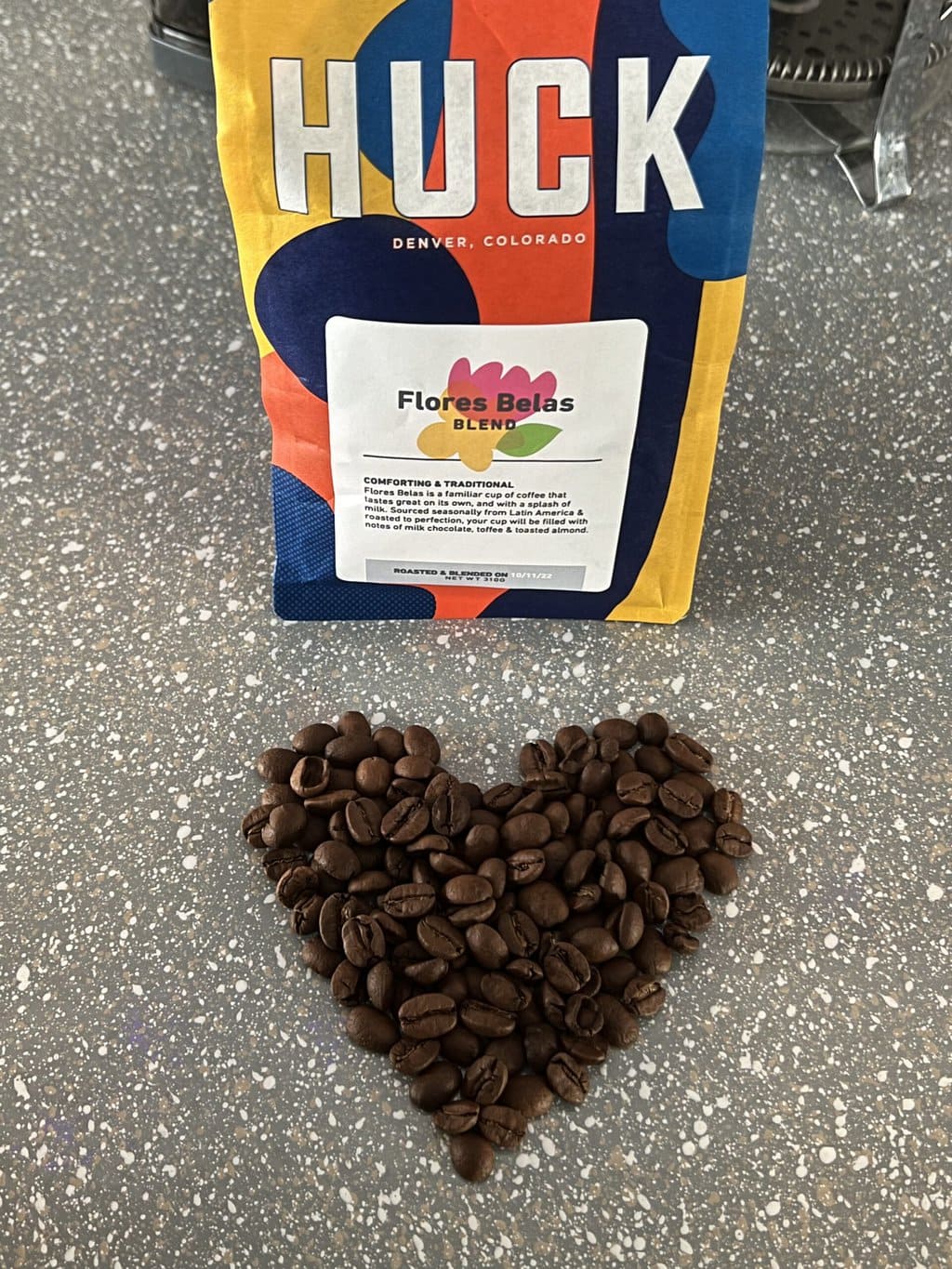 Heart shaped coffee beans next to a pack of Huck Coffee